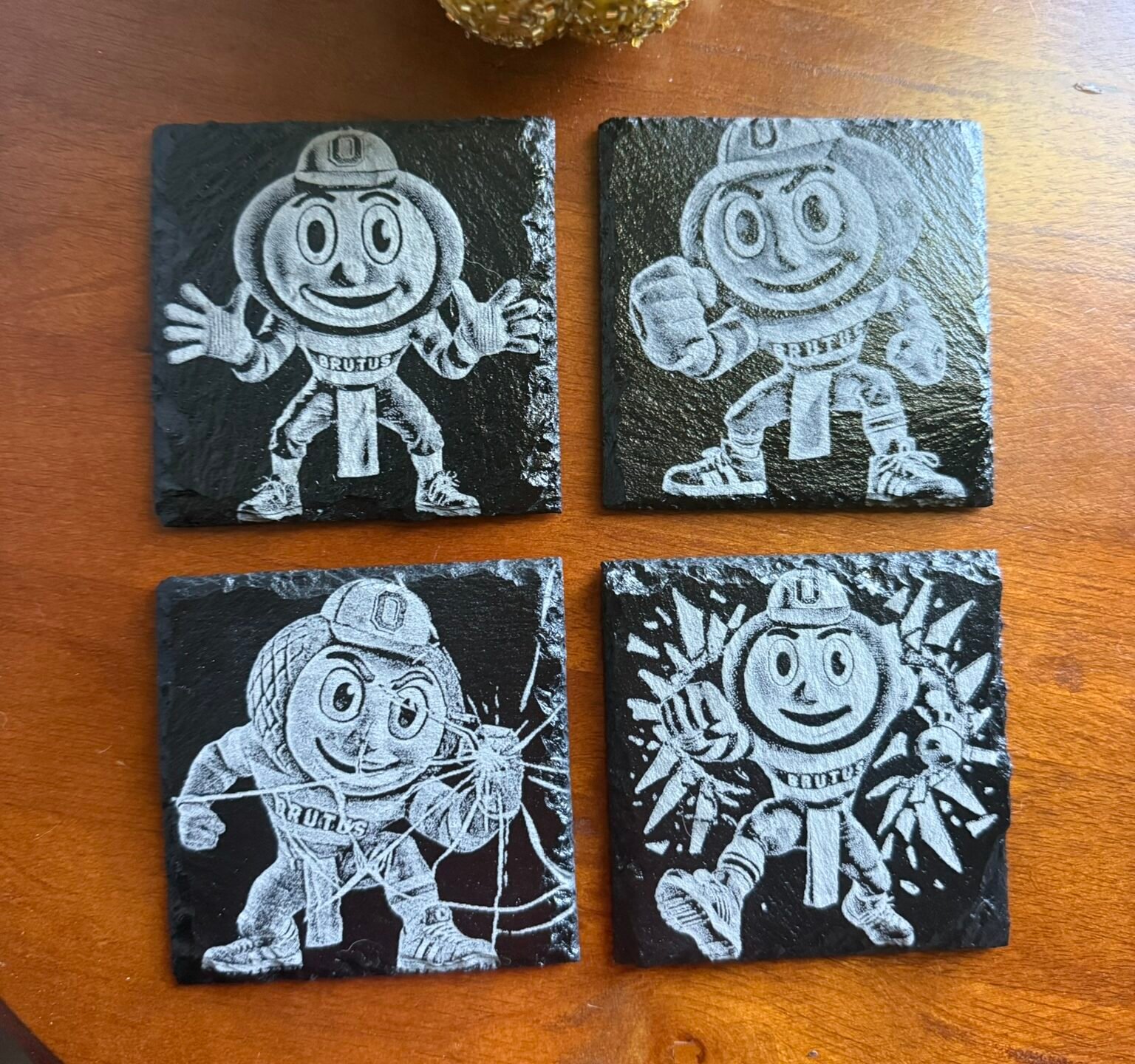 Brutus Buckeye laser-engraved slate coasters on a wooden table